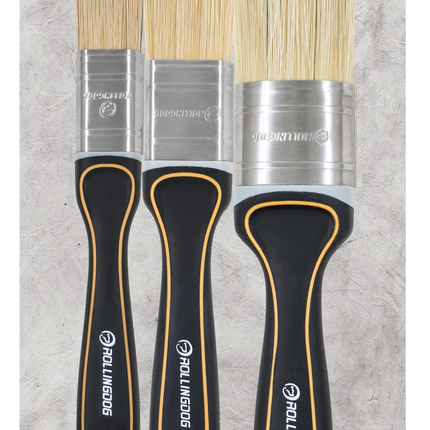 Set of three paint brushes with black handles and bristle heads on a gray background