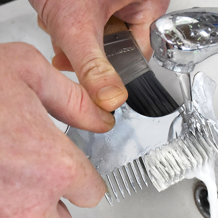 Person cleaning a paint brush with a multifunction tool
