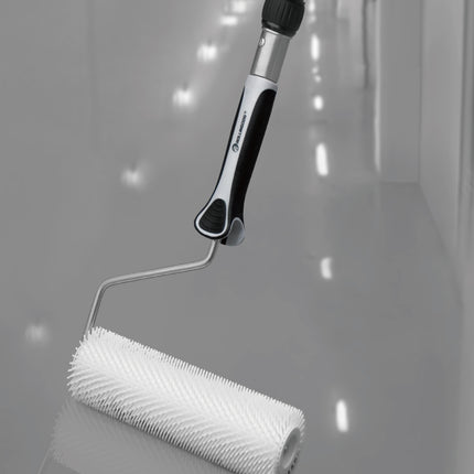 Contractor using spiked roller on epoxy-coated floor with extension pole