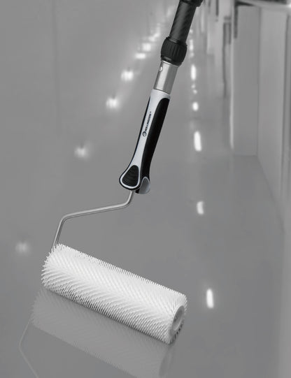 Contractor using spiked roller on epoxy-coated floor with extension pole